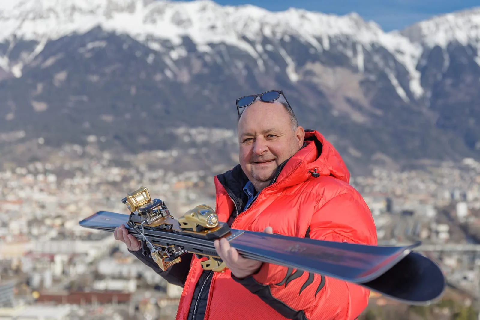 Peter Riedel hält zwei fertige Alpinski quer vor sich und zeigt die Bindungen