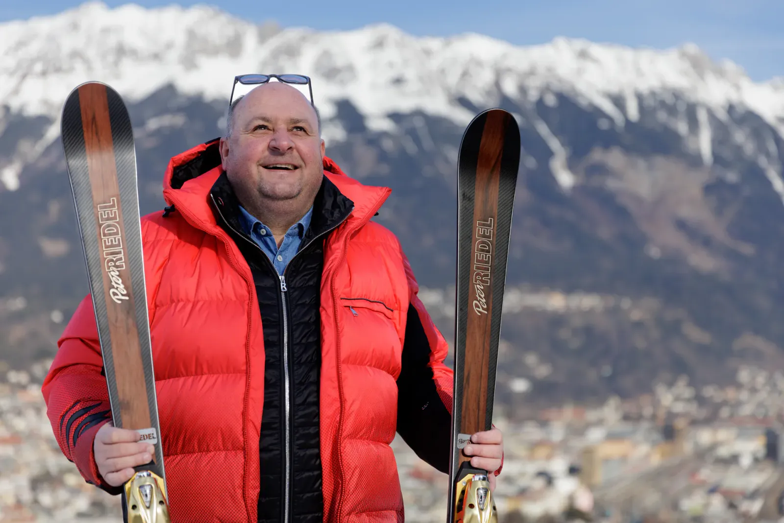 Peter Riedel mit zwei handgefertigten Alpinski vor dem Bergpanorama von Innsbruck