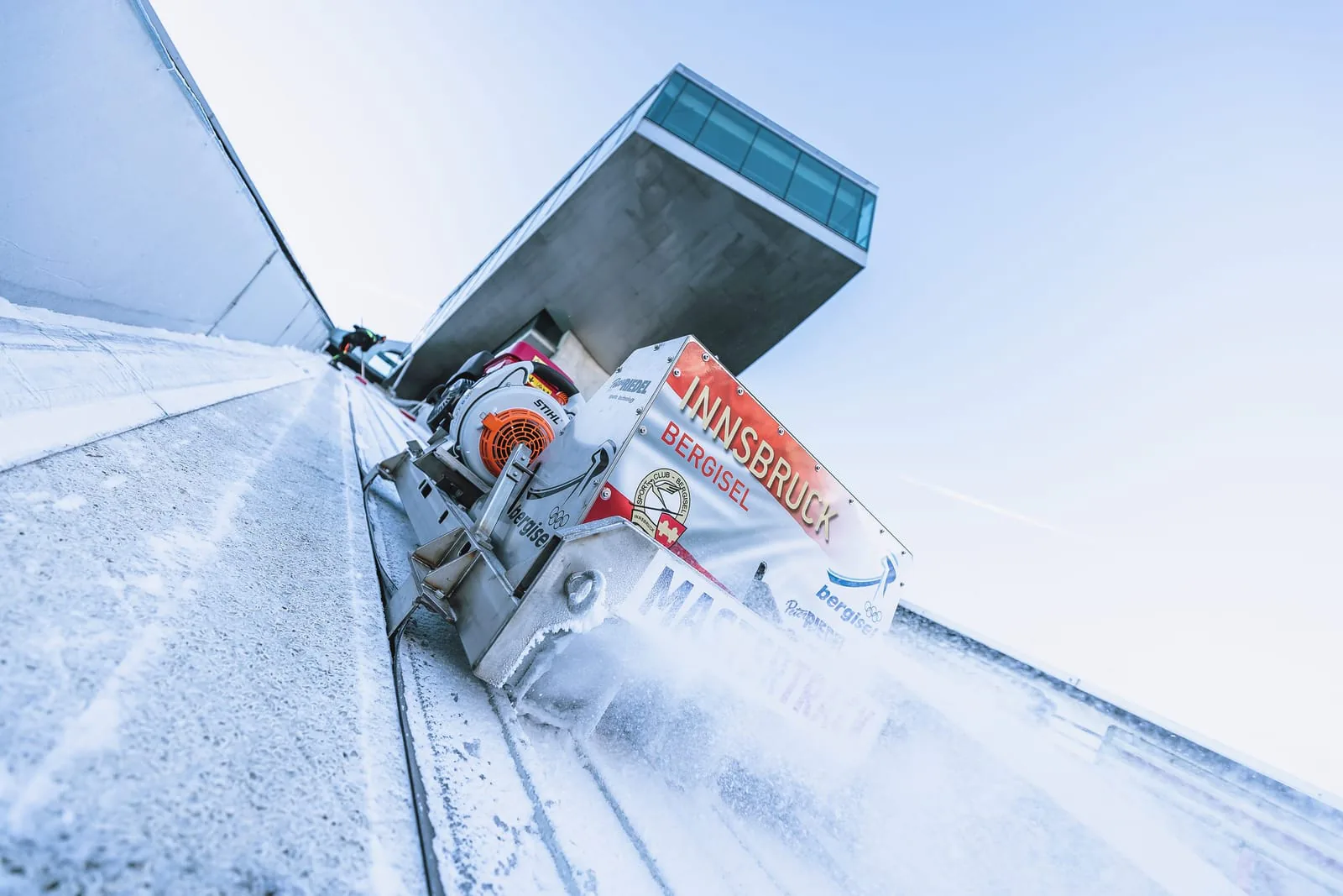 Spurfräse der Peter Riedel GmbH schneidet die Eisspur der Bergiselschanze in Innsbruck, dahinter der Schanzenturm