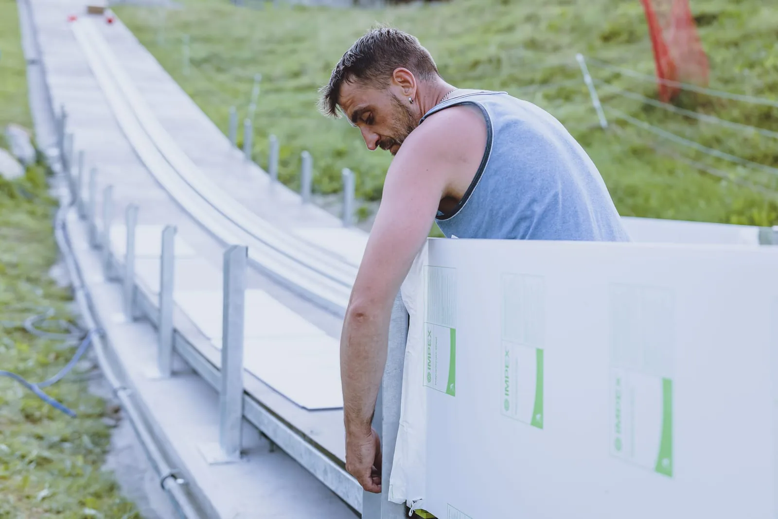Monteur trägt verpackte Kunststoffelemente der CLUBTRACK Anlaufspur zum Anlauf