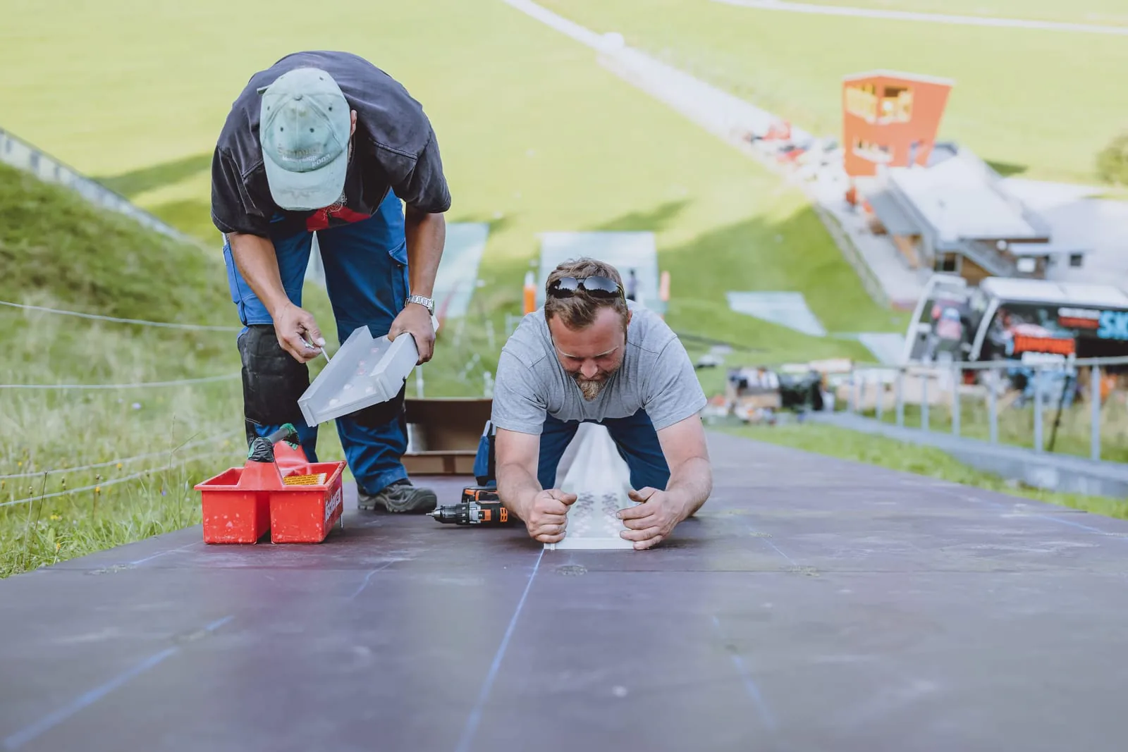 Zwei Monteure verlegen ein Spurelement der CLUBTRACK Anlaufspur auf der Schanze