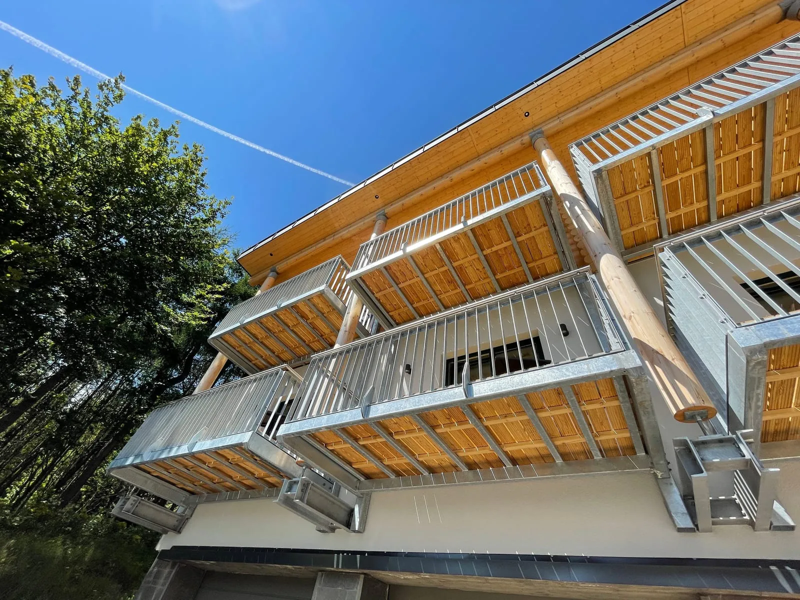 Feuerverzinkte Stahlbalkone mit Holzbelag und Stabgeländer an einem Wohnhaus