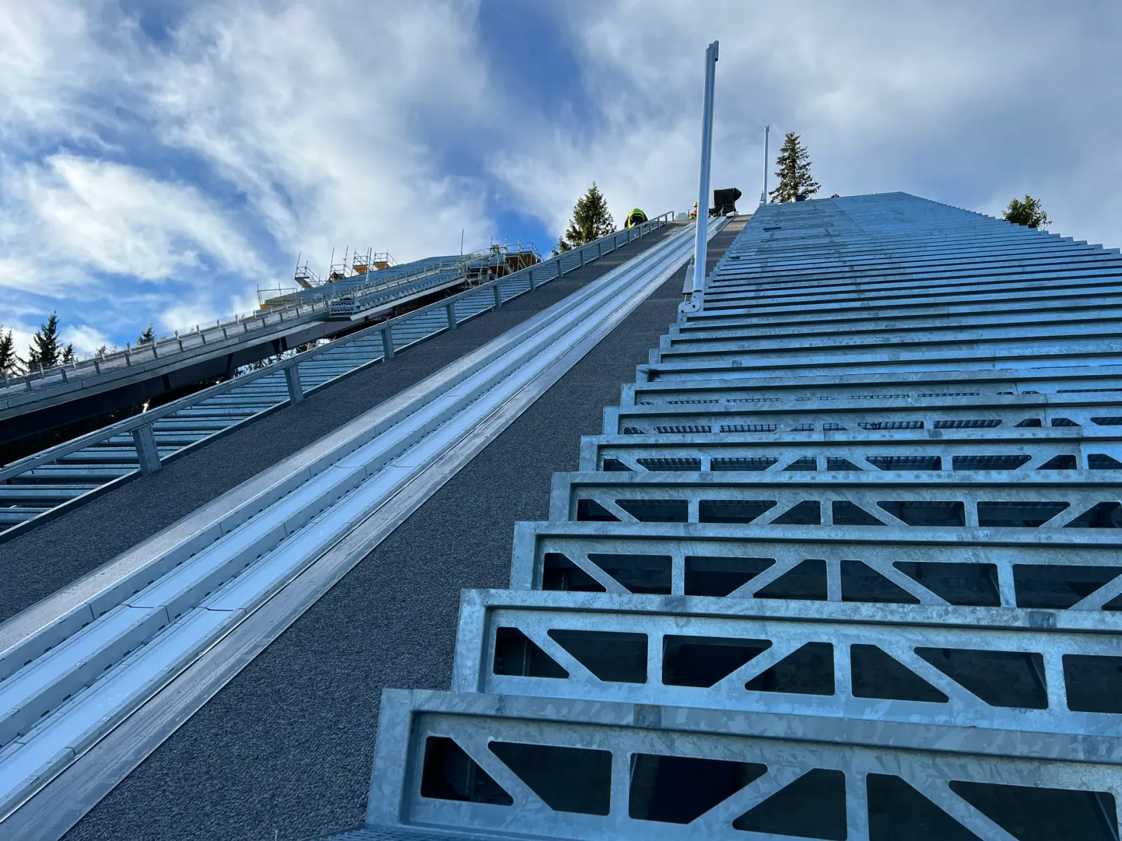 Stahltreppe und Geländer entlang der Anlaufspur einer Skisprungschanze